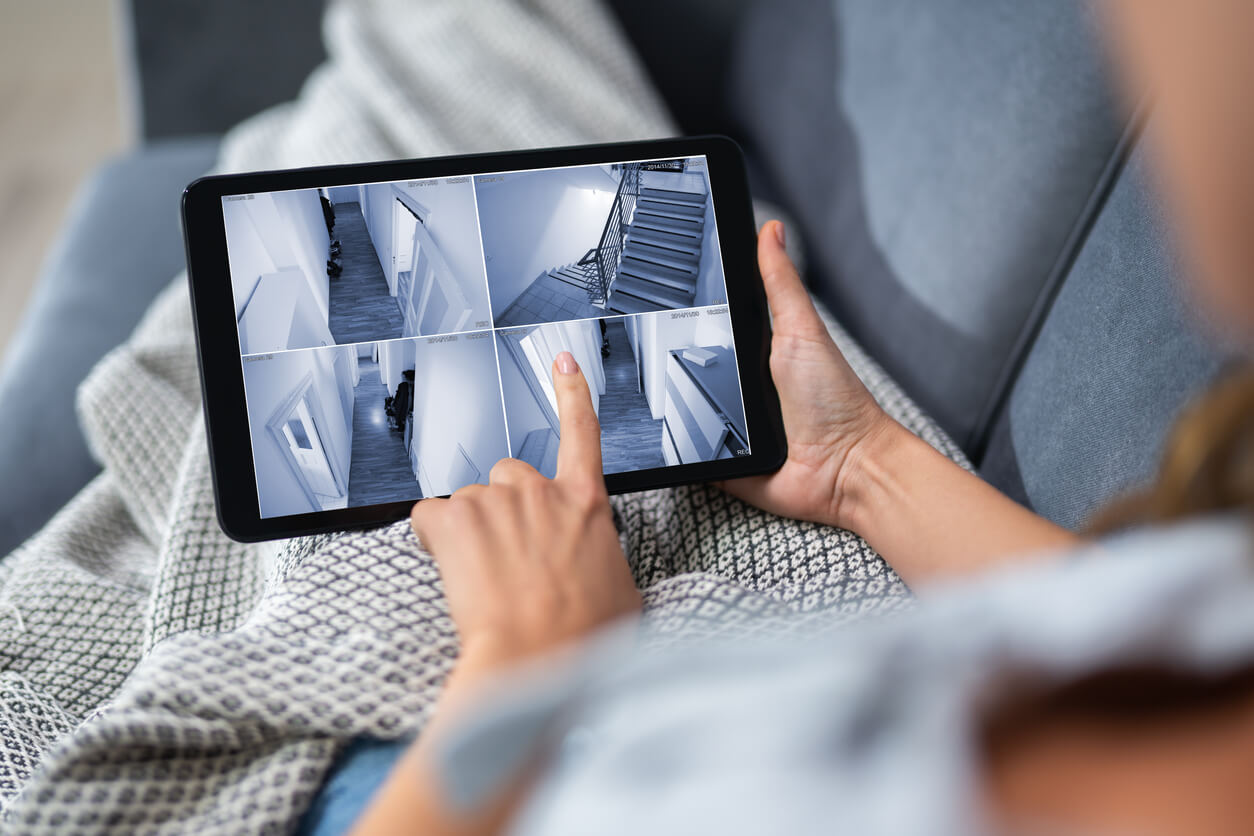 Person schaut auf einem Tablet Kameraaufnahmen von Ihrem Zuhause an.