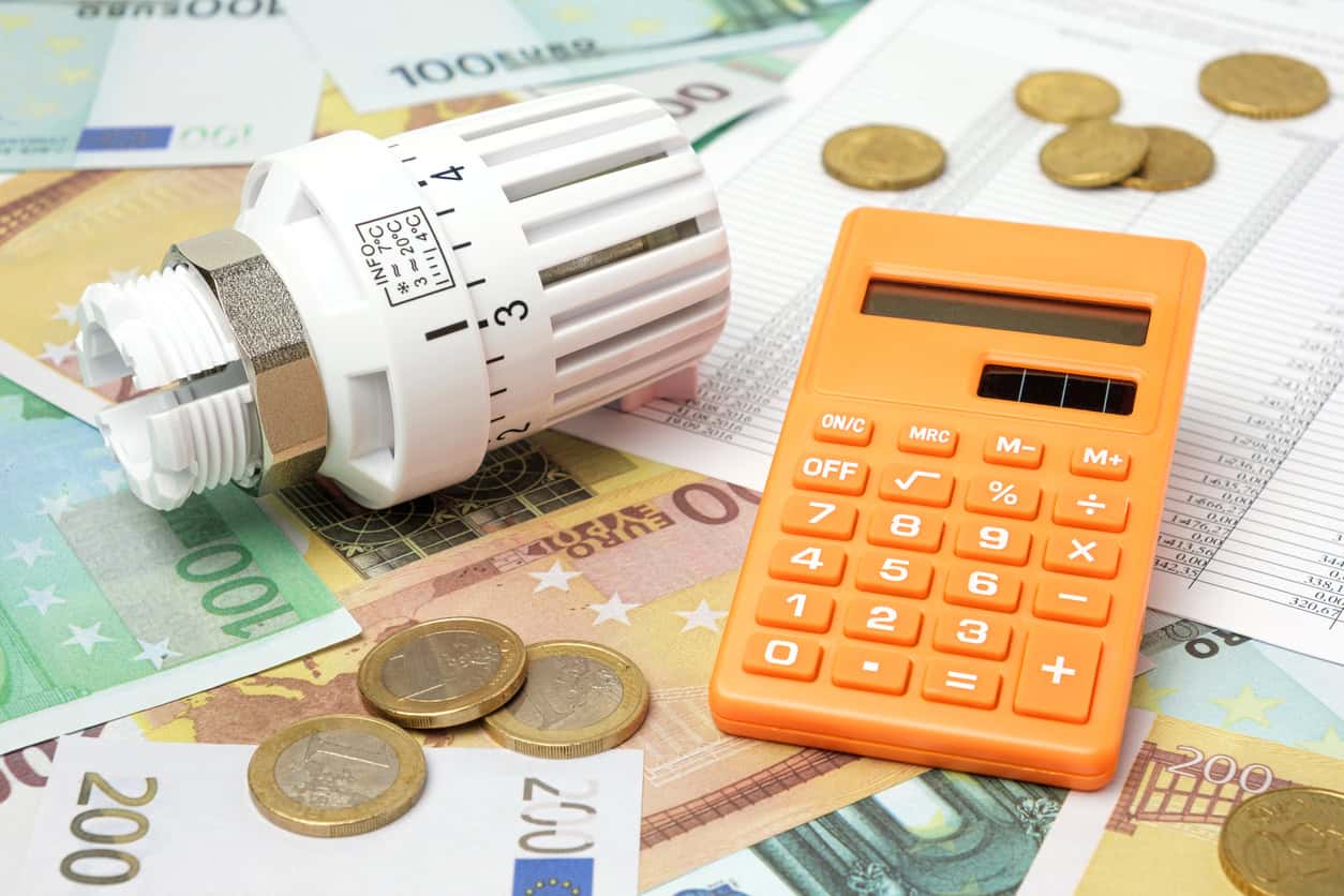 Energiearmut: Ein Taschenrechner und Heizkörperthermostat liegen auf Geld und einer Rechnung